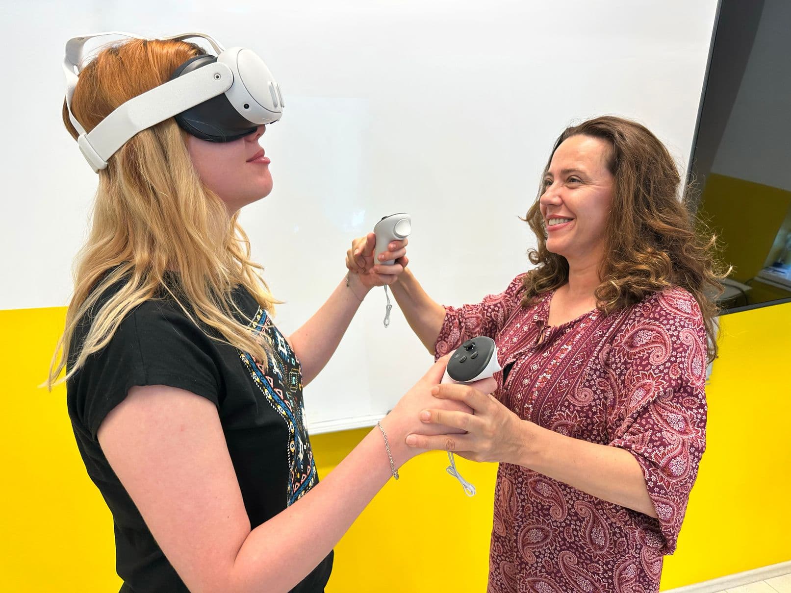 A trainer guides a teacher holding VR controllers in a Jantar classroom