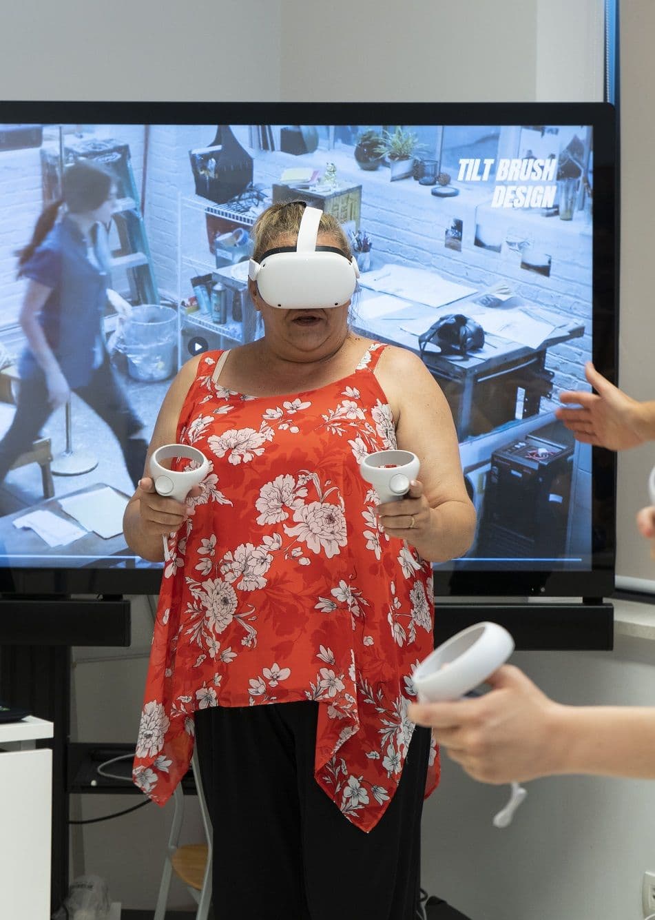 A teacher in a VR headset while the screen behind her shows what she sees