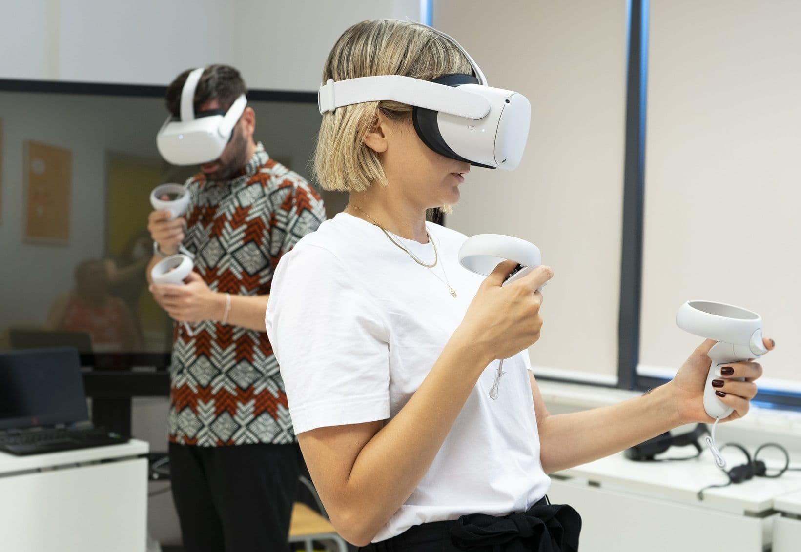 Two teachers wearing VR headsets and holding controllers